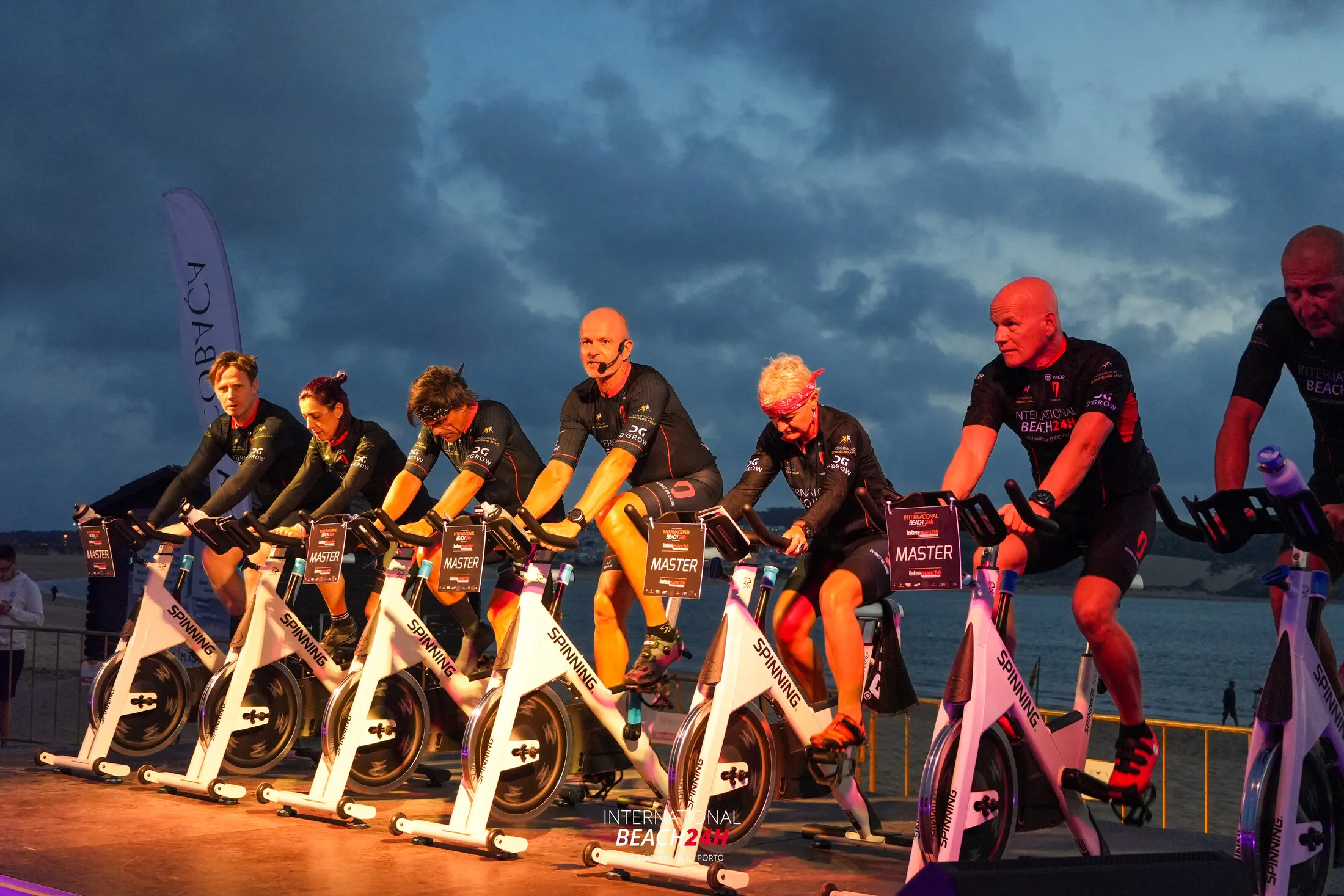Instructors on stage at dusk under warm light and a blue sky at Beach24H